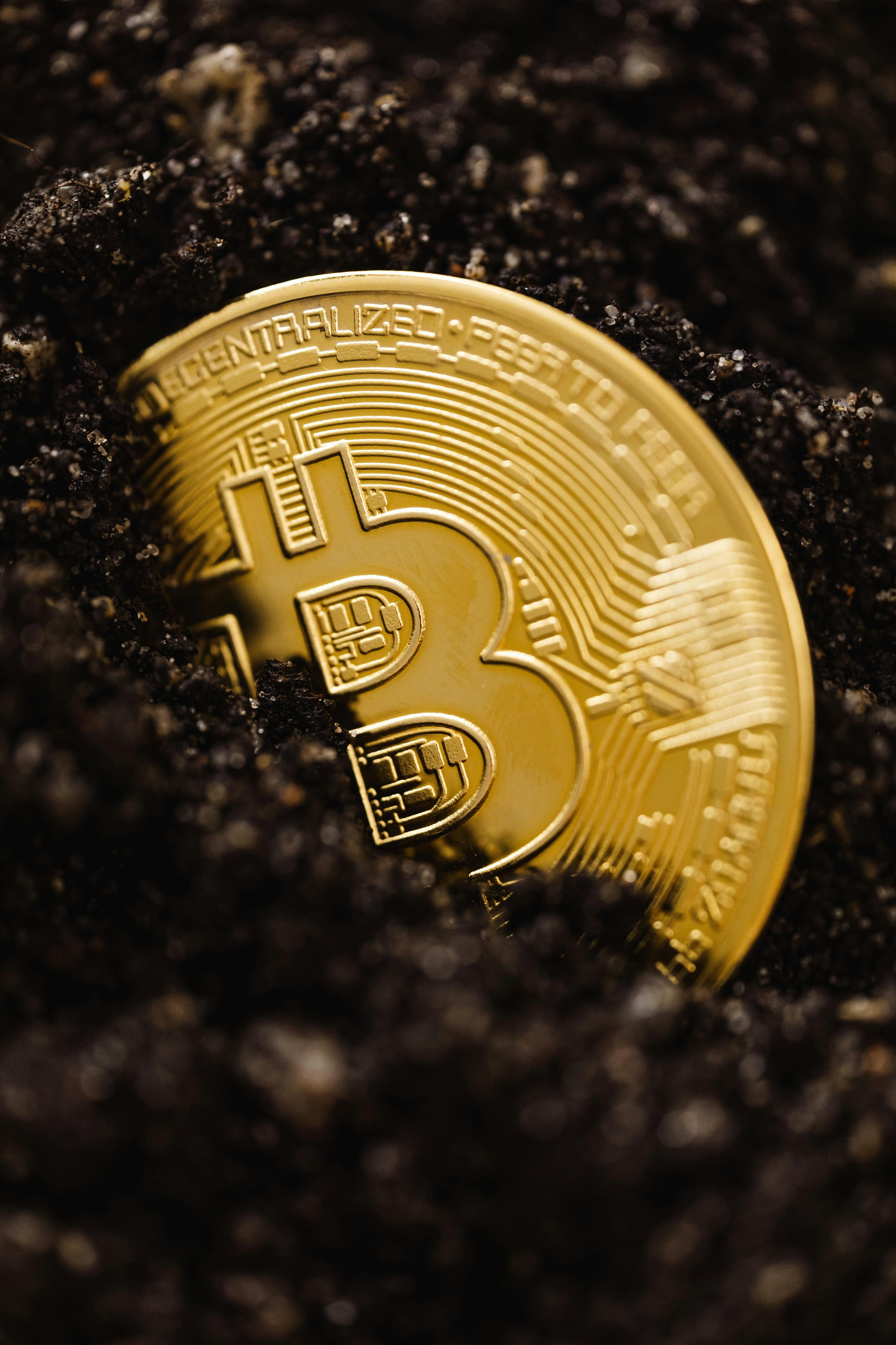 半埋在深色土壤中的金色比特币硬币,象征隐藏的价值和长期加密投资。